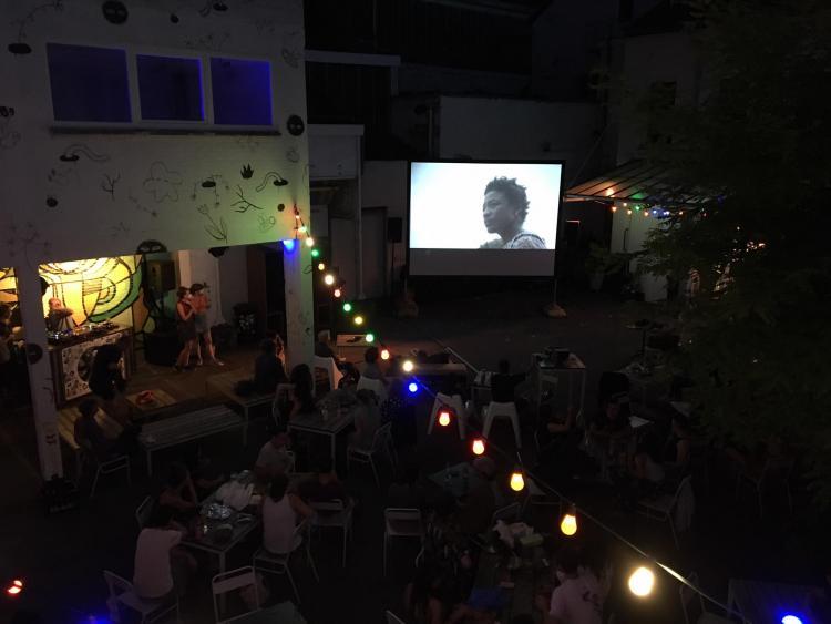 public regardant un écran de cinéma en plein air dans la pénombre