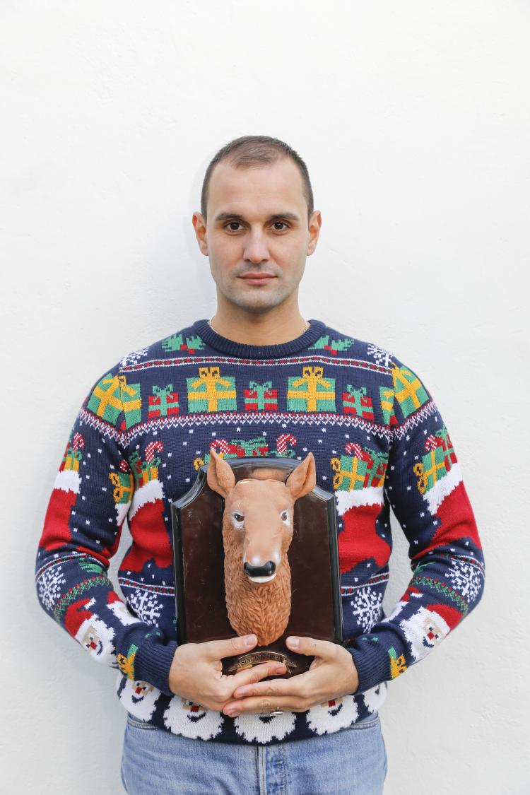 homme en pull de Noël portant un buste de renne en bois