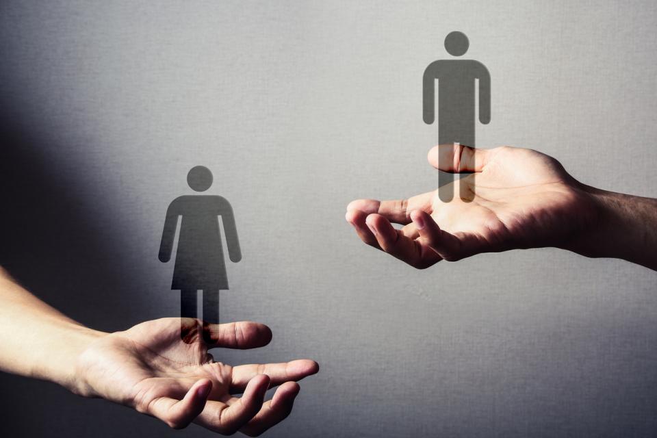 Deux mains, l'une tenant une silhouette de femme et l'autre une silhouette d'homme