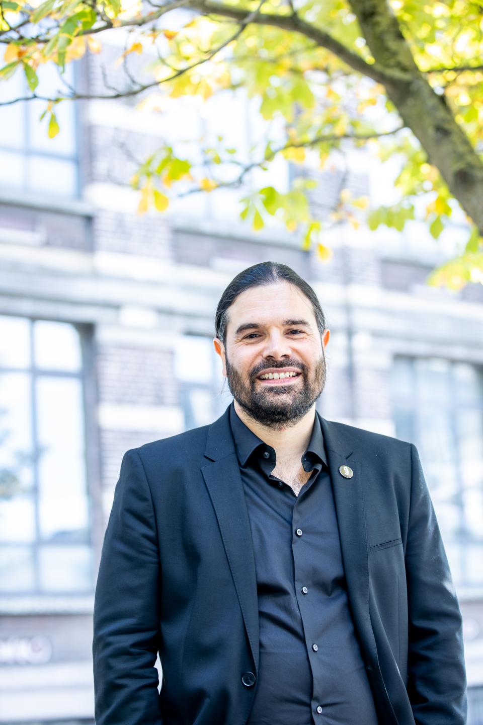 Portrait de Fabrice Laurent devant un bâtiment et un arbre